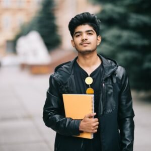 handsome-young-indian-student-man-holding-notebooks-while-standing-street_231208-2773